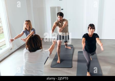 Man and women practicing yoga in exercise class Stock Photo