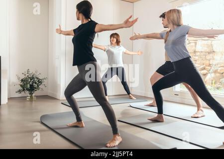 Man and women practicing yoga with instructor in health club Stock Photo