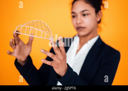Businesswoman with architectural model against yellow background Stock Photo