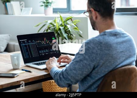 Businessman analyzing stock data on laptop at home Stock Photo