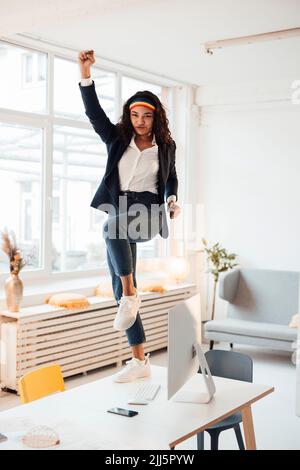 Businesswoman dancing on desk in office Stock Photo