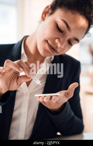 Smiling young businesswoman taking pregnancy test Stock Photo