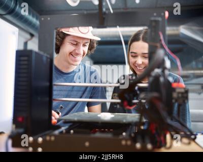 Smiling engineers working with 3d printer at workshop Stock Photo