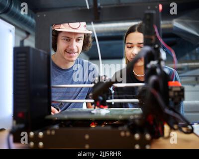 Engineer and colleague operating 3d printer working at workshop Stock Photo