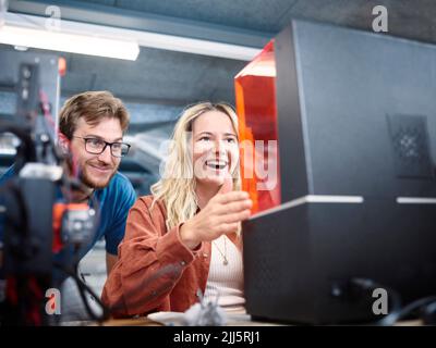 Happy technicians looking at SLA printer in workshop Stock Photo