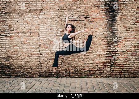 Young ballet dancer dancing in front of brick wall Stock Photo