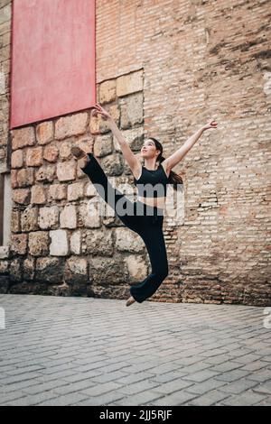 Woman practicing ballet near brick wall Stock Photo