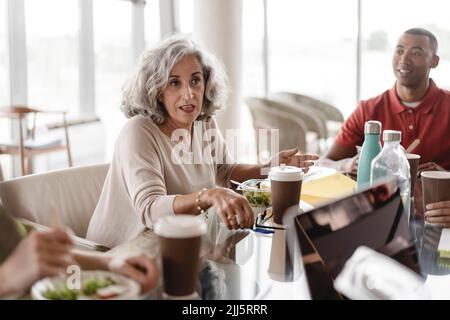 Senior businesswoman sitting with businessman discussing at table in office Stock Photo