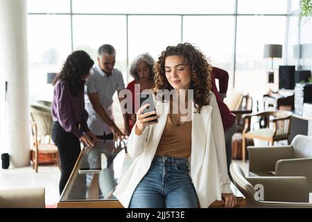 Businesswoman using smart phone sitting at desk Stock Photo