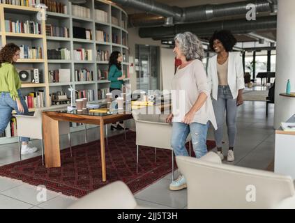 Happy senior businesswoman with colleagues enjoying at office Stock Photo