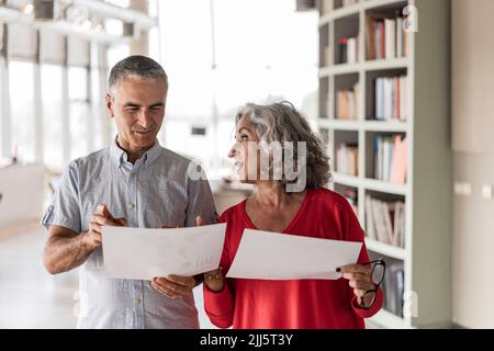 Smiling businessman with colleague discussing at office Stock Photo