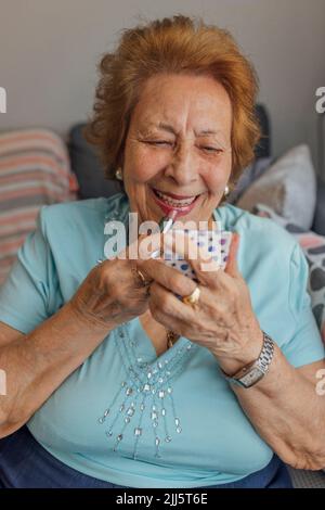 Happy senior woman applying lipstick Stock Photo