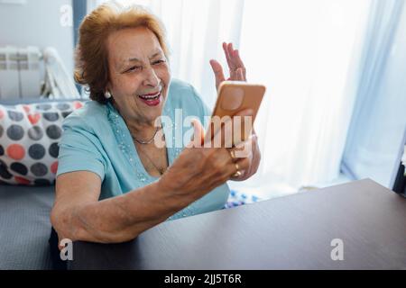 Happy senior woman using smart phone at home Stock Photo