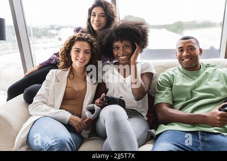 Smiling young woman playing video games with friends Stock Photo