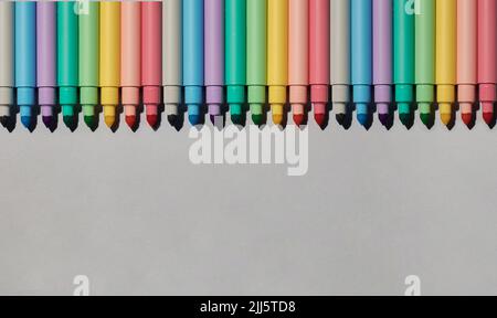 Studio shot of row of colorful felt tip pens lying against gray background Stock Photo