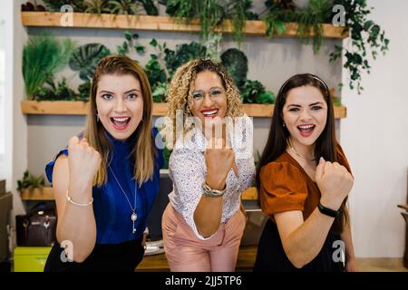 Excited business colleagues clenching fists in office Stock Photo