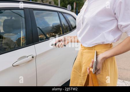 Businesswoman pressing button on key to lock car Stock Photo