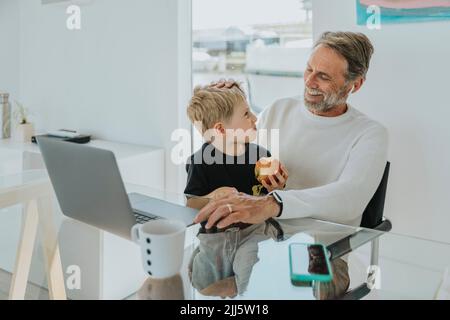 Happy father with son sitting at table Stock Photo
