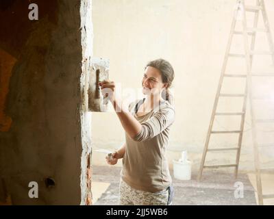 Happy painter plastering wall with spatula Stock Photo