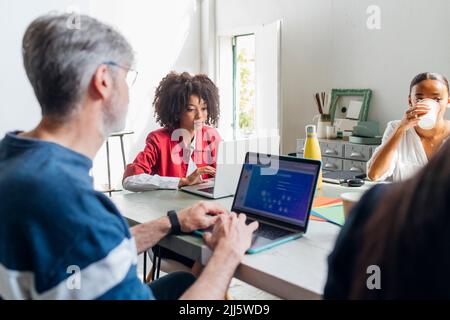 Business colleagues working on laptops in coworking office Stock Photo