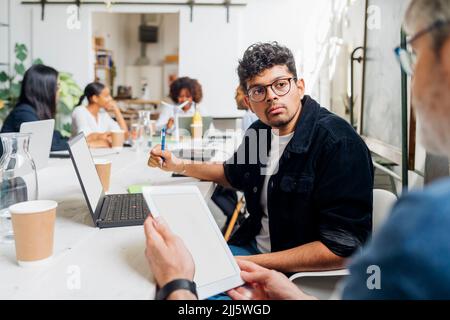 Businessman looking at colleague in office meeting Stock Photo