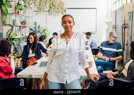 Smiling young businesswoman by multiracial colleagues at desk in office Stock Photo