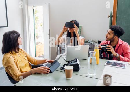 Businesswoman wearing VR goggles by multiracial colleagues in office Stock Photo