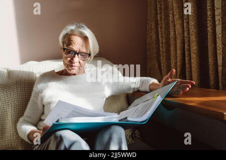 Senior woman with eyeglasses reading documents at home Stock Photo