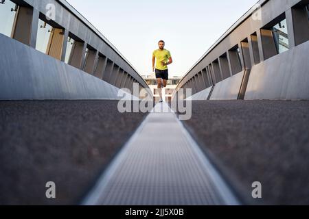 Young man jogging on footbridge Stock Photo
