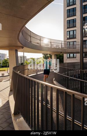 Young man jogging on footbridge Stock Photo