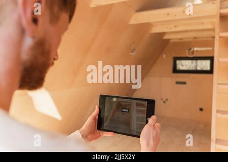 Man using tablet pc to visualise home interior at new wooden eco house Stock Photo