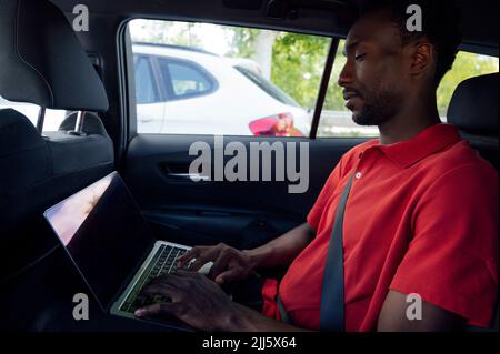 Man on laptop sitting in car Stock Photo