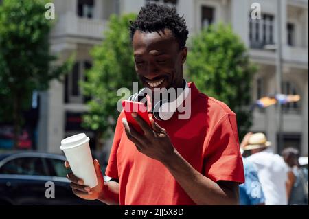 Smiling man with coffee cup using mobile phone Stock Photo