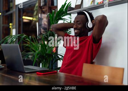Smiling man with hands behind head sitting in cafe Stock Photo