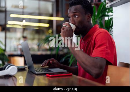 Man drinking coffee sitting with laptop at cafe Stock Photo