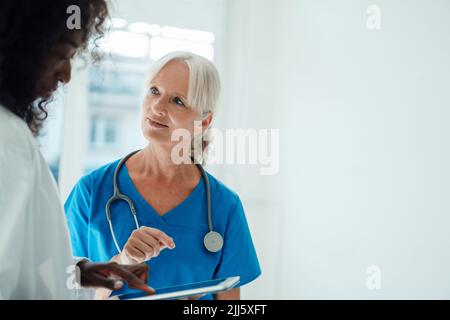 Female doctor pointing at tablet PC standing by colleague Stock Photo