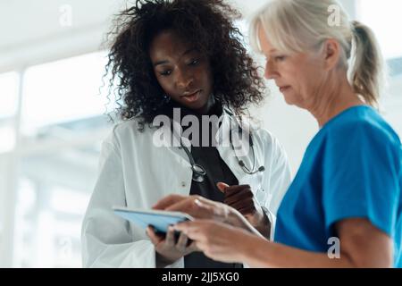 Female doctor using tablet PC standing by colleague Stock Photo
