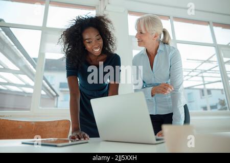 Smiling businesswomen discussing over laptop at desk in office Stock Photo