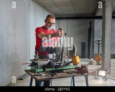 Mature plumber cutting plastic pipe Stock Photo