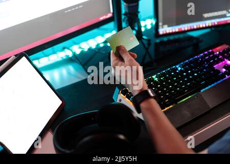 Man holding credit card in front of desktop PC at home Stock Photo
