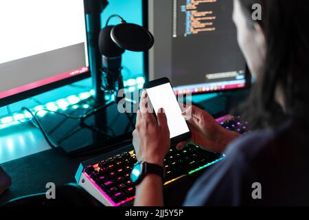 Man using smart phone in front of desktop PC at home Stock Photo