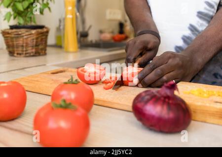 Hands of man cutting tomatoes in kitchen Stock Photo