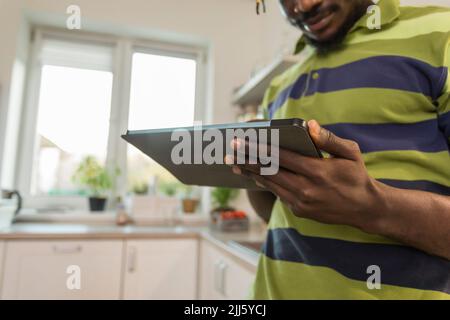 Hands of man using tablet PC in kitchen Stock Photo