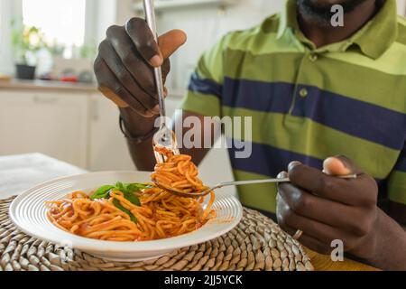 Hands of man holding fork with spaghetti at home Stock Photo