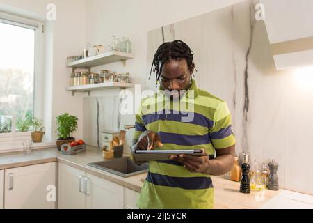 Man using tablet PC in kitchen Stock Photo