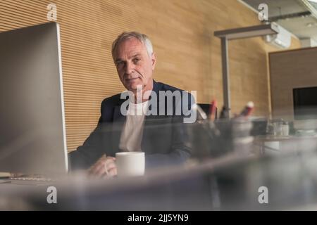 Confident businessman with desktop PC at work place Stock Photo