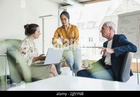 Businesswoman discussing over tablet PC with colleagues in office Stock Photo