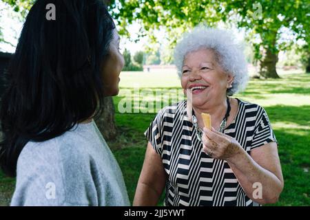 Happy mother with daughter eating ice cream in park Stock Photo