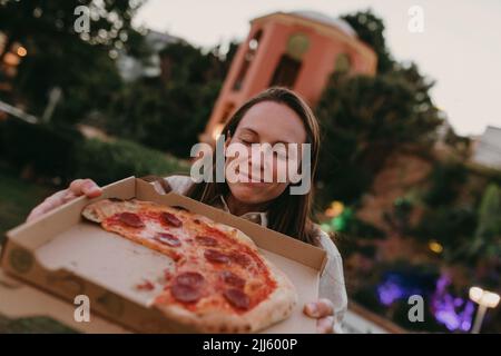 Woman with eyes closed showing pizza in box Stock Photo