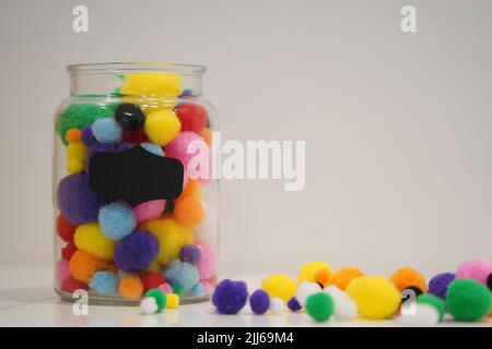 Colourful pom pom on a jar with background space for text. Background for art and crafts uses. Stock Photo